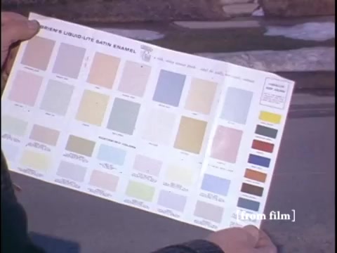 Suburban street where two men review a color palette; typical home in the background.