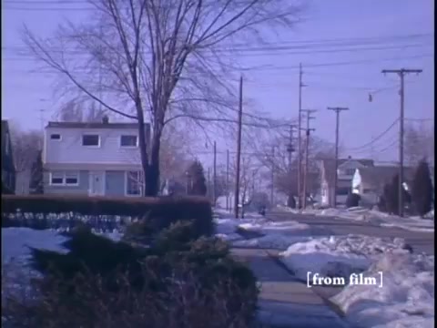Residential house flanked by telephone poles and a snow-covered sidewalk.
