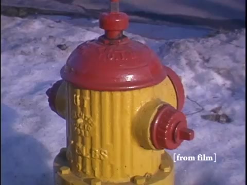 Yellow fire hydrant capped with a red lid in a solitary winter street moment.